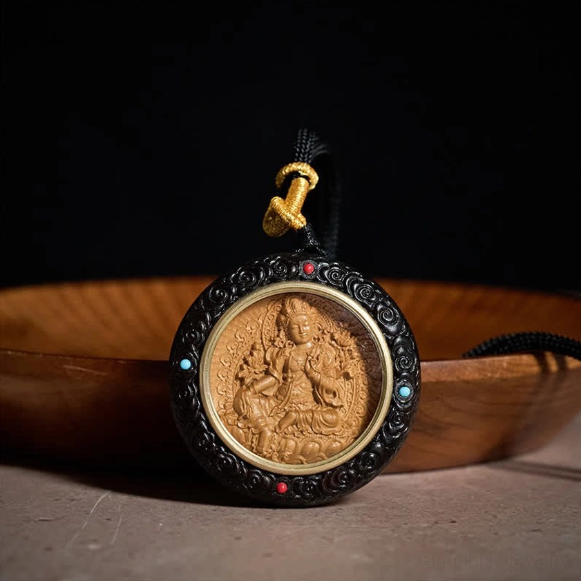 Green Tara Buddhist protector deity pendant close-up showing carving details and stone inlays