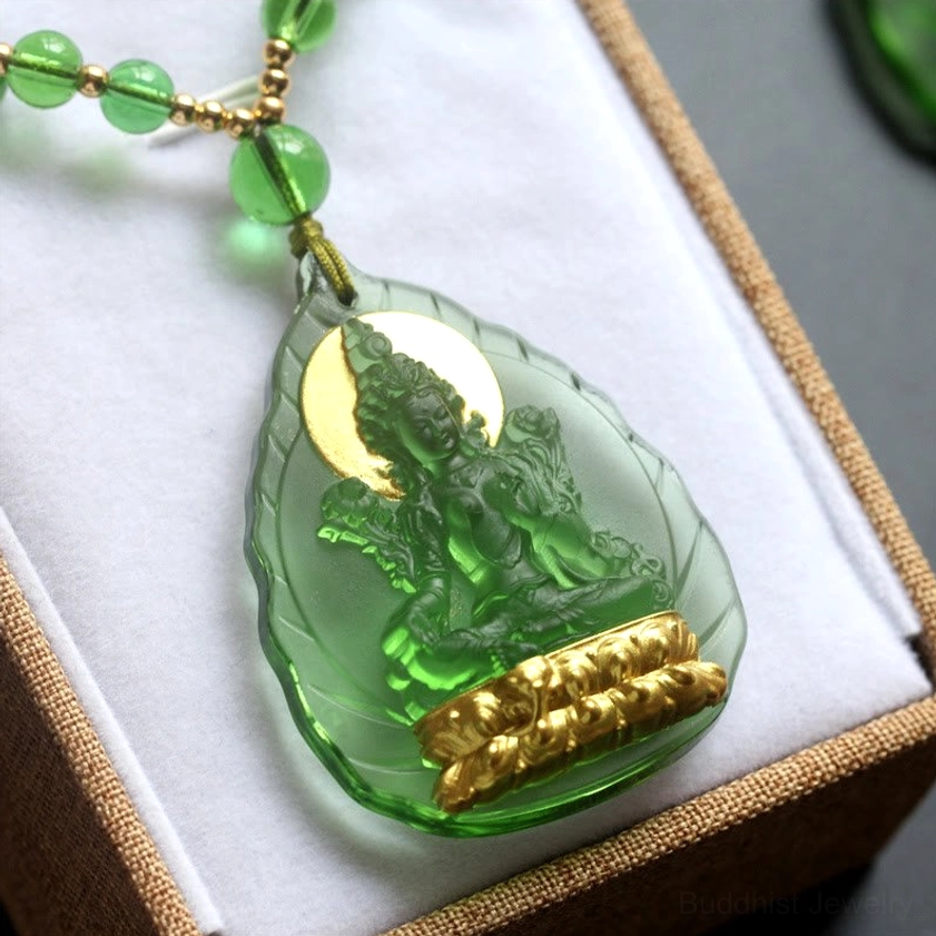 Green Tara Buddha liuli pendant close-up on white velvet display showing gold-plated connector and chain detail
