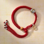 Green Tara silver charm Buddhist red string bracelet with carved bead detail, oblique angle view
