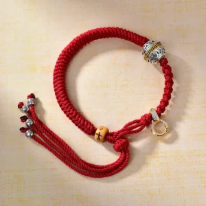 Green Tara silver charm Buddhist red string bracelet with carved bead detail, oblique angle view