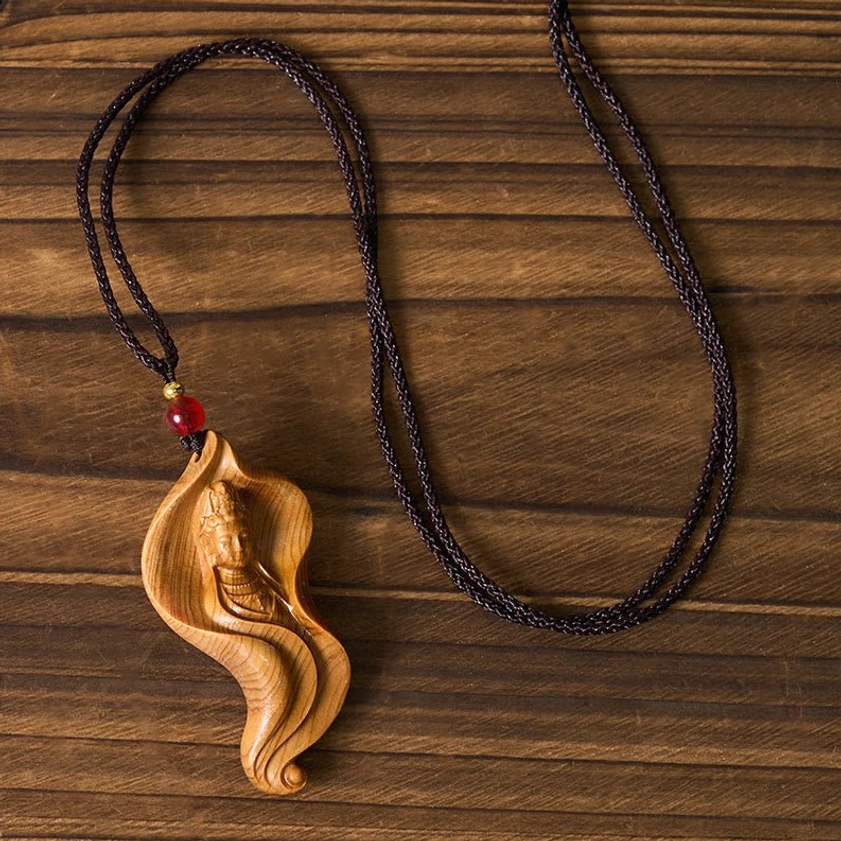 Top view of Guanyin Avalokiteshvara wood pendant showing lotus leaf carving and braided cord