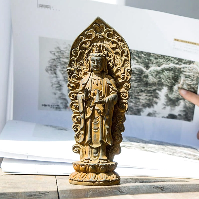Side profile view of handmade Guanyin Buddha statue showing intricate details of robes, sacred symbols and artistic craftsmanship on wooden table