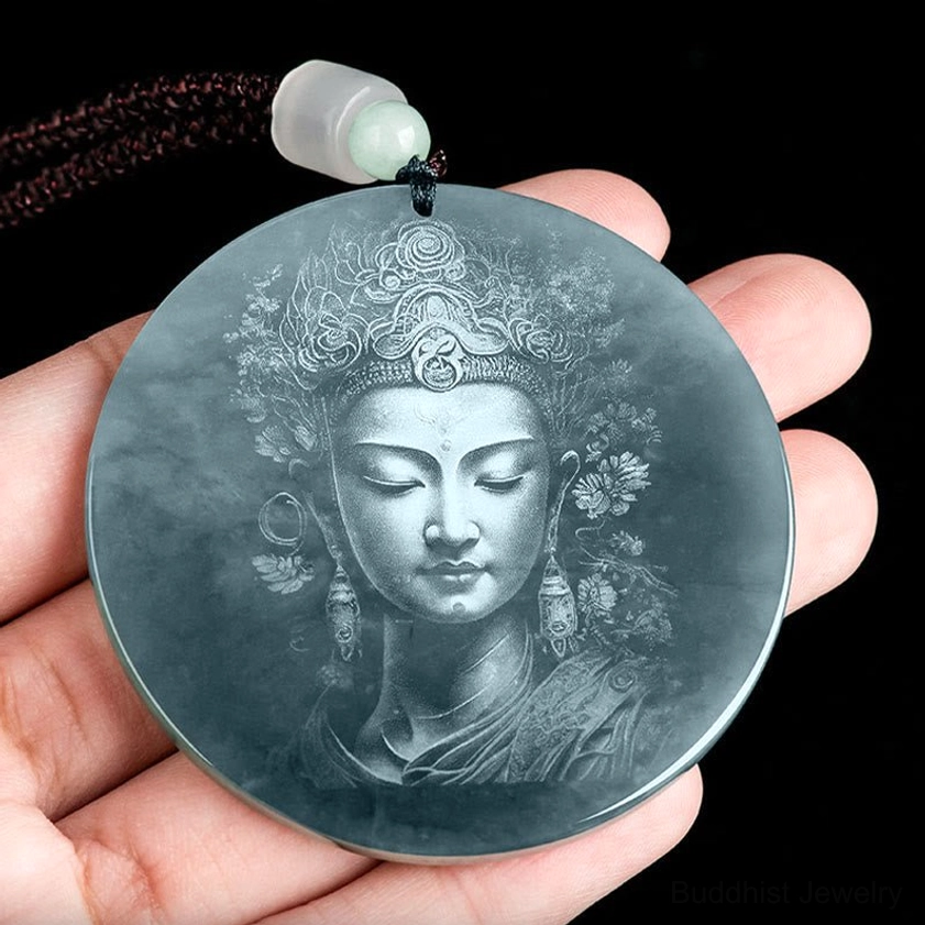 Hand holding round Guanyin jade pendant showing size and natural polish