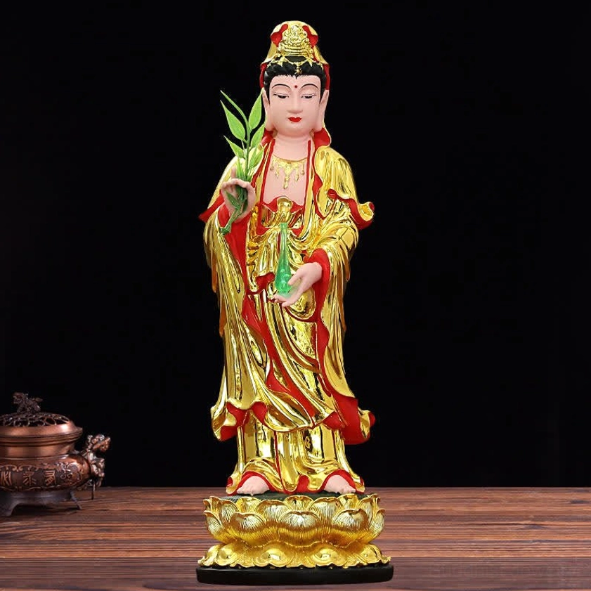 Guanyin resin statue with red-gold robes, willow branch, jade vase, and lotus base on styled tabletop