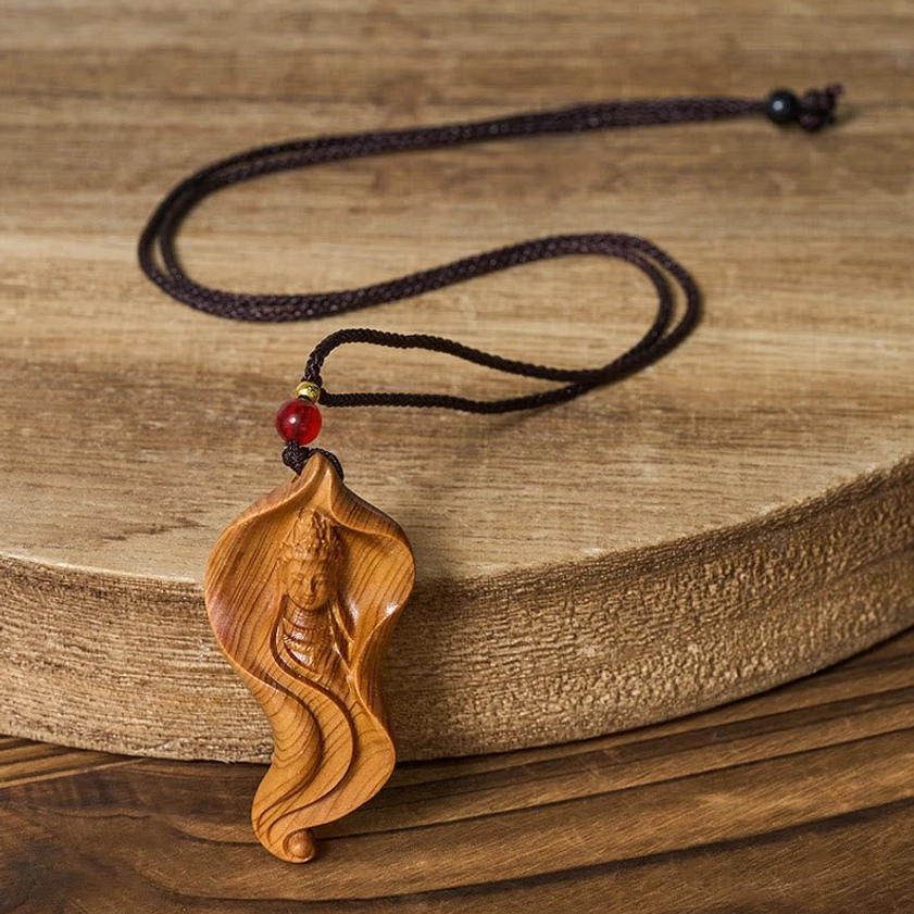 Side profile of handmade Guanyin wood pendant on black braided necklace cord with red bead detail