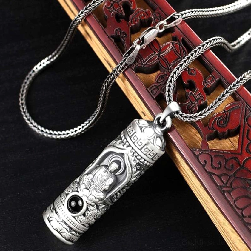 Zodiac Buddha pendant with wheat-link chain necklace on carved wooden background, side view detail