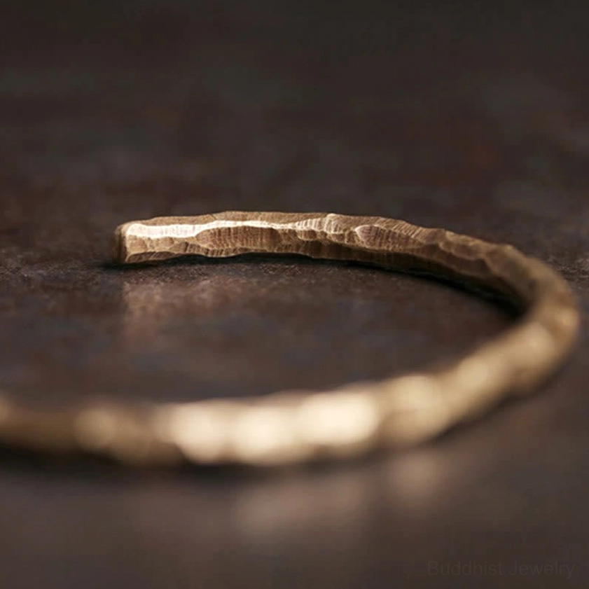 Hammered brass spiritual cuff bracelet low-angle side view, highlighting artisanal craftsmanship and metallic sheen
