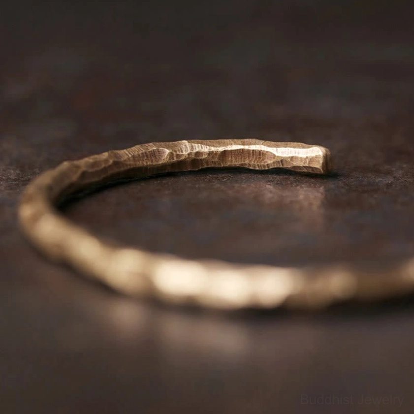 Hammered brass spiritual prosperity bracelet low-angle edge view, emphasizing textured metallic finish and artisanal quality