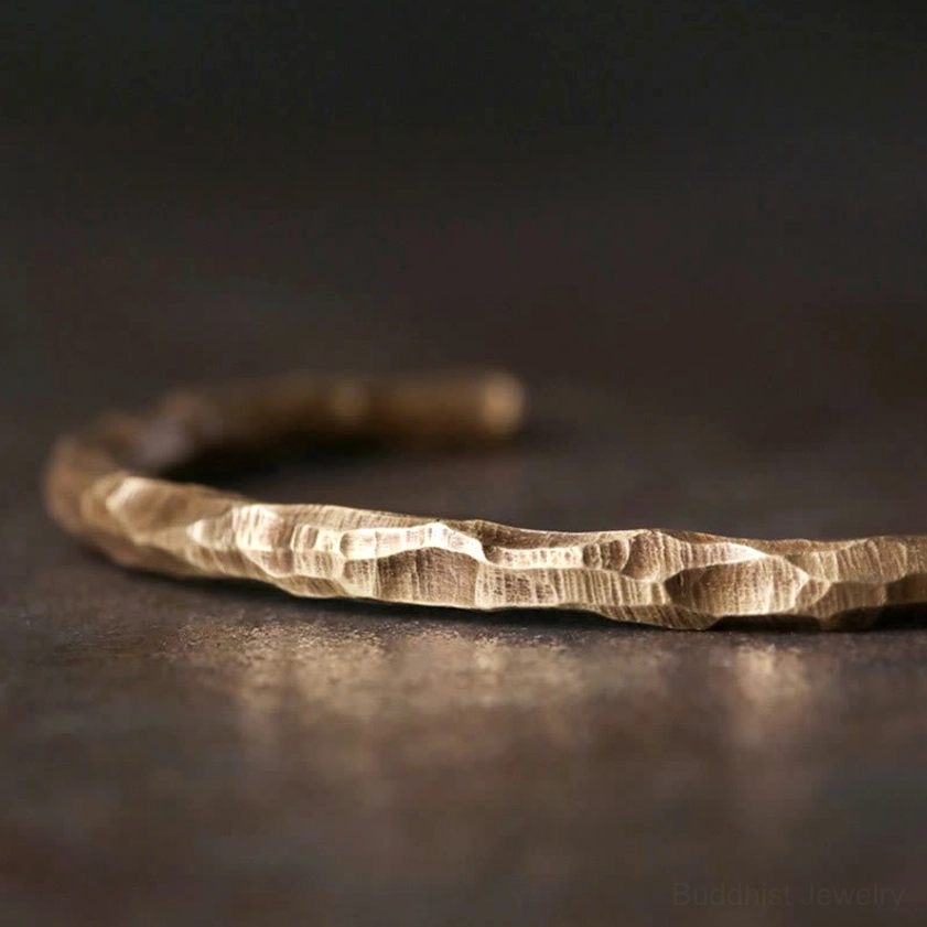 Hammered brass cuff bracelet side flat lay, revealing detailed bumpy surface texture and open cuff adjustable design