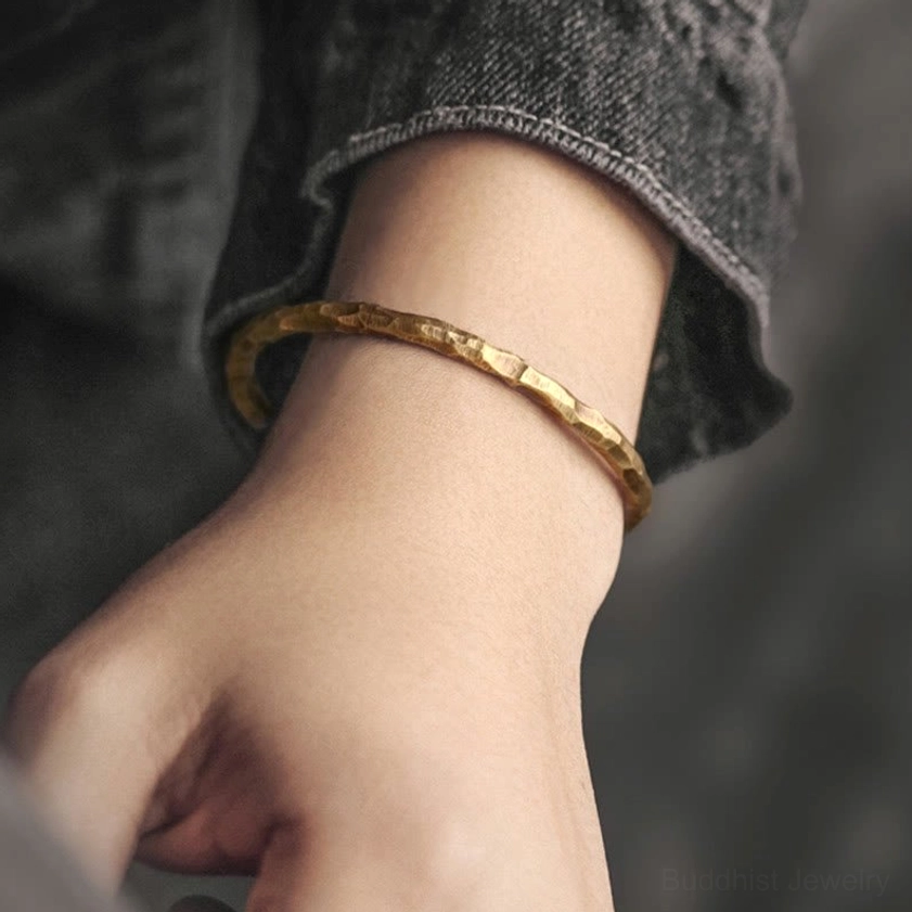 Hammered brass cuff bracelet worn on wrist, demonstrating adjustable fit and textured gold tone finish for daily wear and energy enhancement