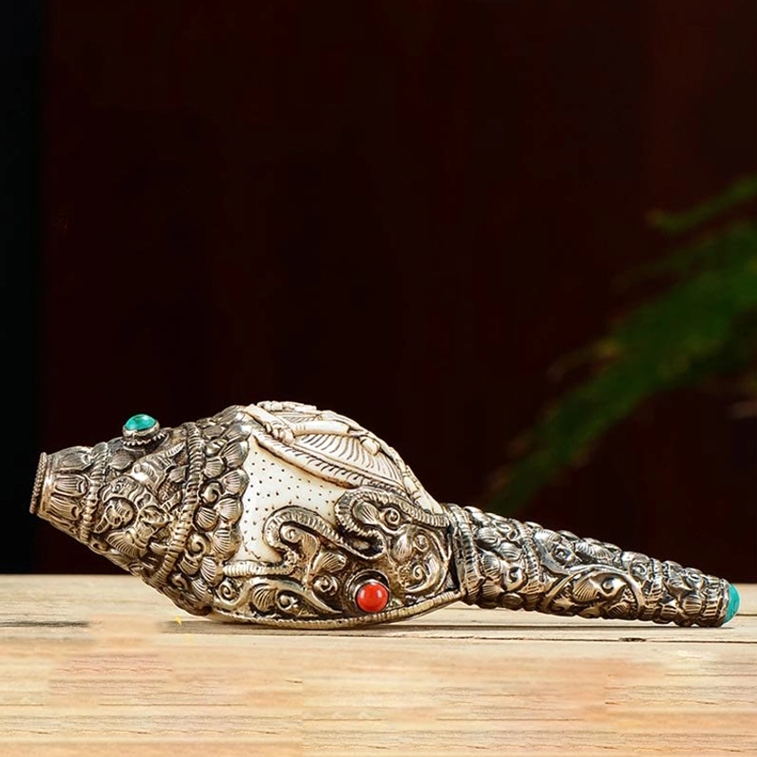 Single carved shankha conch shell with detailed Buddha relief and ornate silver filigree