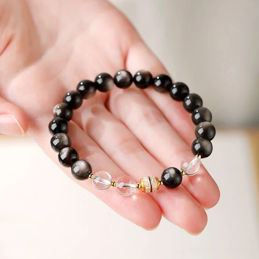 Silver Sheen Obsidian Buddhist bracelet held in palm showing craftsmanship details with black beads, clear spacers and gold accents