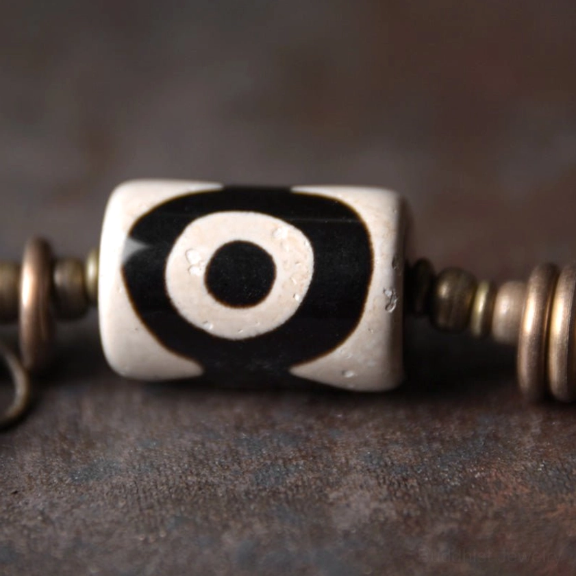 Front view flat lay of hand-painted dzi bead showing classic black and white round eye pattern design