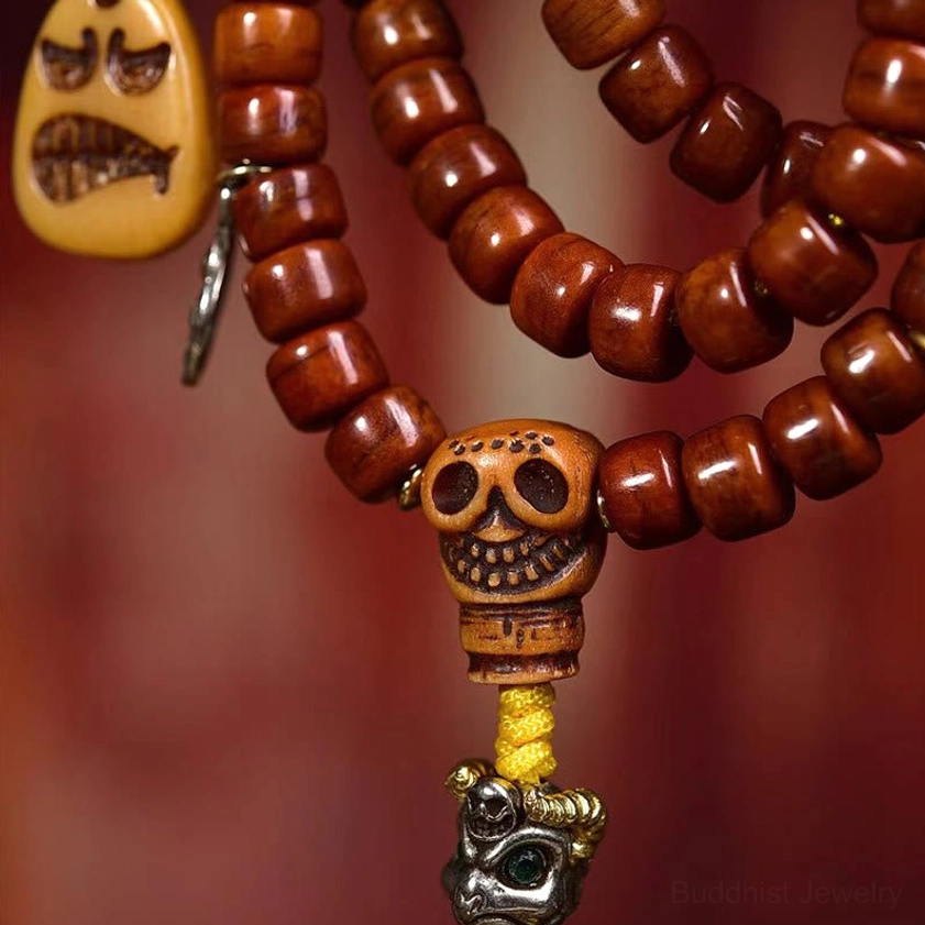 Premium bone bead Buddhist mala showing hand-painted Dzi amulet, skull guru bead, grimace pendant with detailed metal components on red background