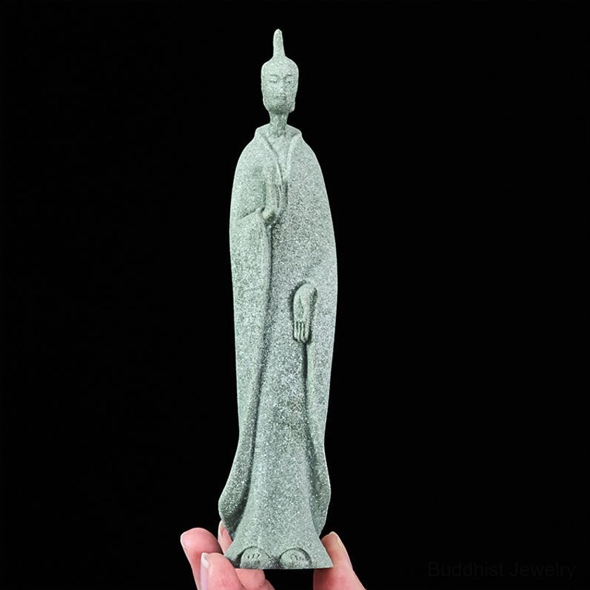 Standing Buddha figurine in hand displaying detailed carving and matte sandstone finish with traditional design