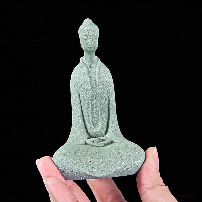 Delicate Buddha figurine held between fingertips showing miniature detail and lightweight portable spiritual decor