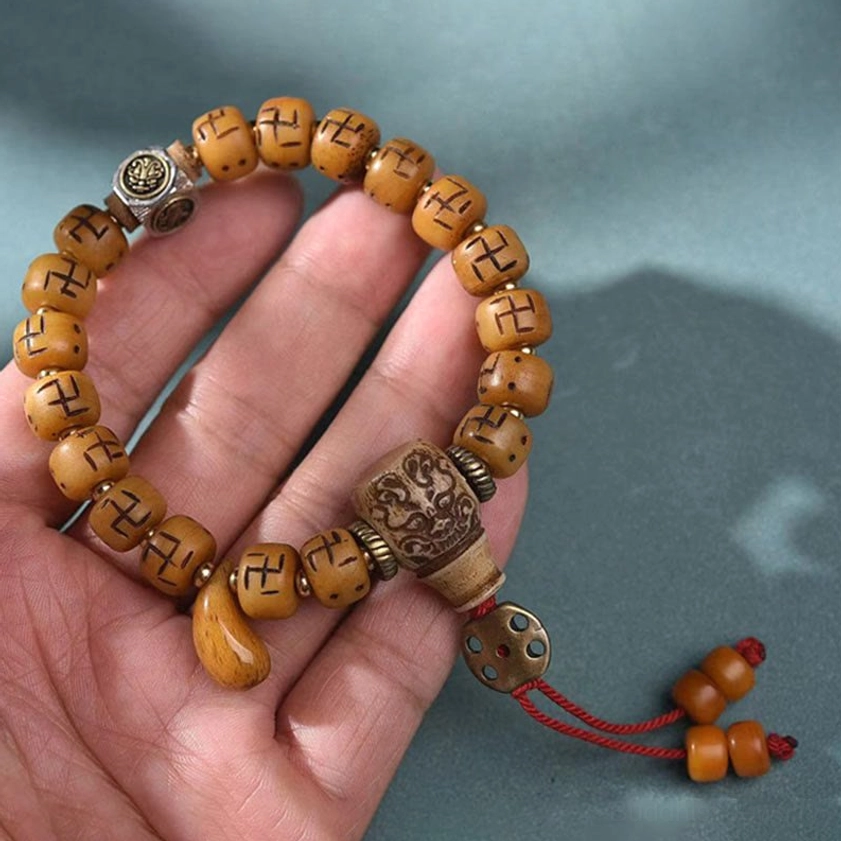 Handcrafted Buddhist bracelet with bone beads, spiritual charms, protective Dzi bead, and woven tassel detail