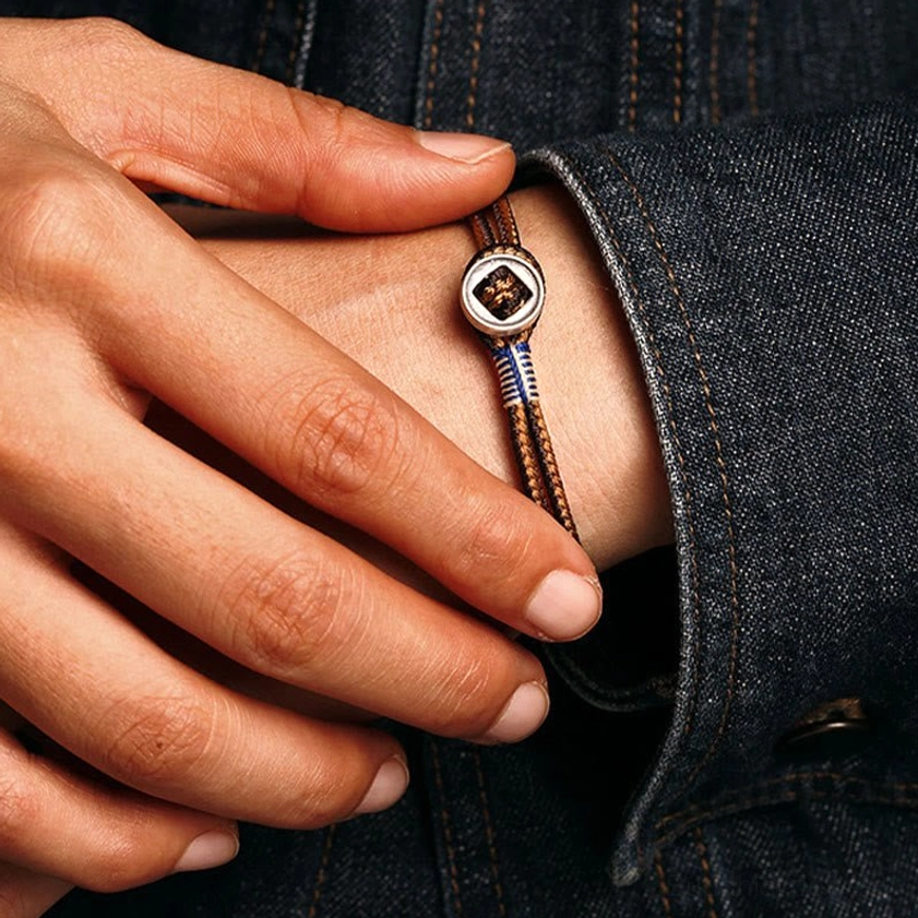 Authentic handcrafted Buddhist protection bracelet featuring natural woven string and sterling silver metal accents