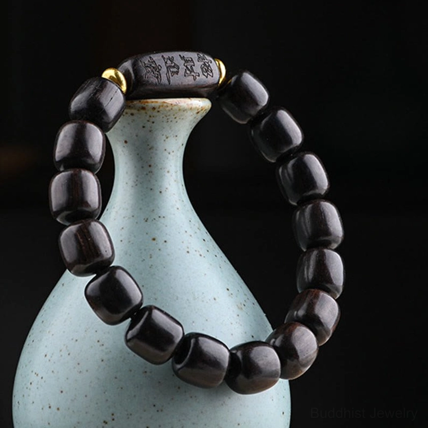 Handcrafted ebony wood bracelet showing natural grain texture and carved Buddhist charm beads with metal accents