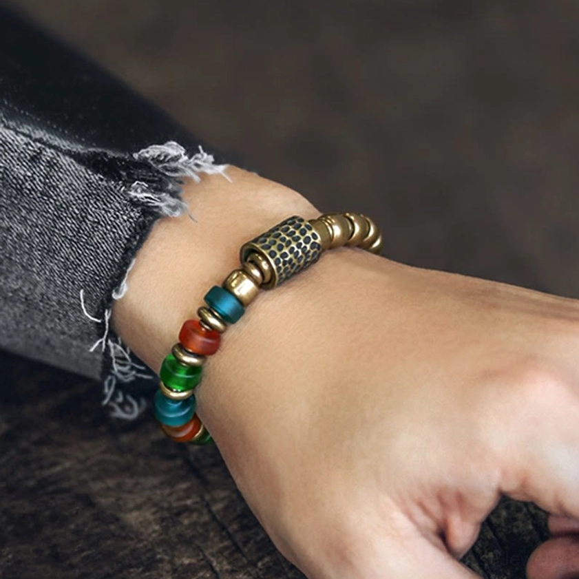 Handcrafted mixed glass and copper beaded bracelet lifestyle shot on wrist with denim and wooden background