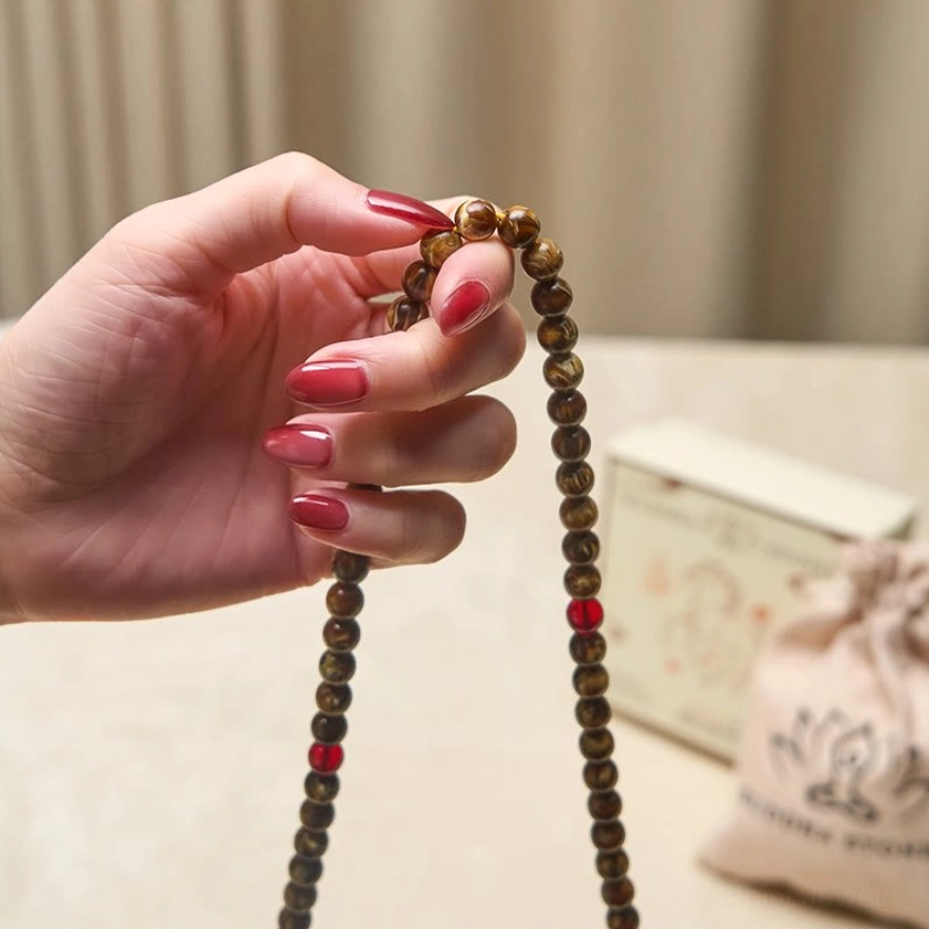 Handheld 108 amber mala beads with red accent beads held in hand - close-up meditation beads detail