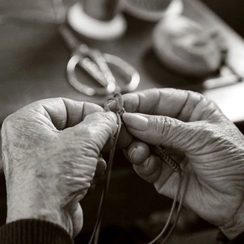 Artisan handcrafting Buddhist string bracelet in traditional workshop, vintage black and white craftmanship scene