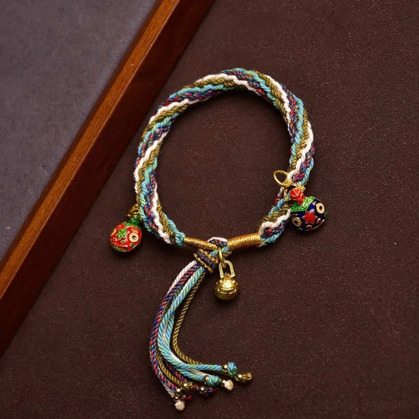 Hand-braided Buddhist fortune bracelet with gold bell and cloisonné family charms close-up detail