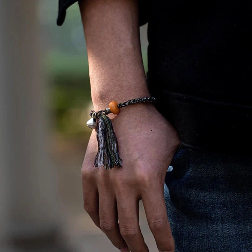 Sterling silver amber bracelet with protective tassel detail worn on dark clothing background