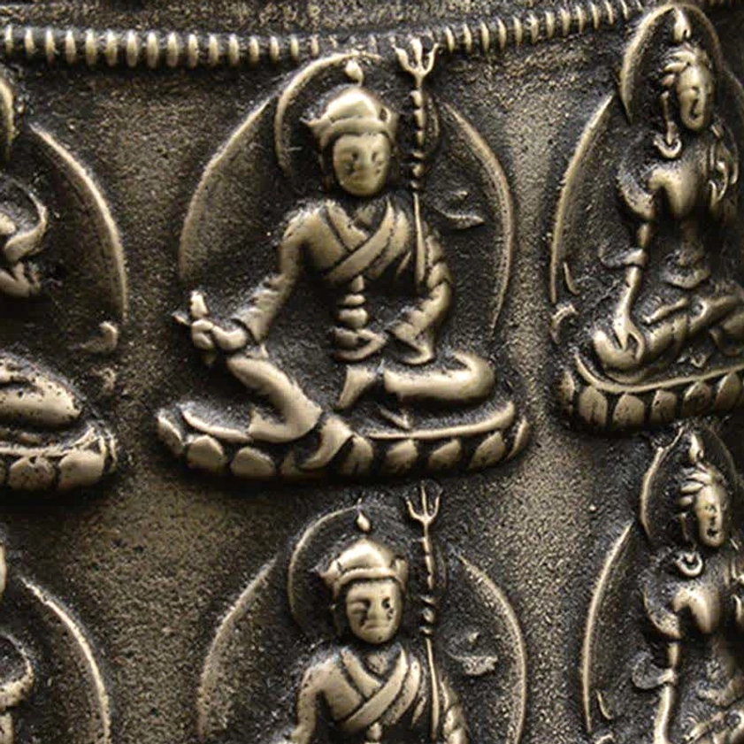 Tight side close-up of embossed Buddhist deity reliefs with aged bronze raised finish texture