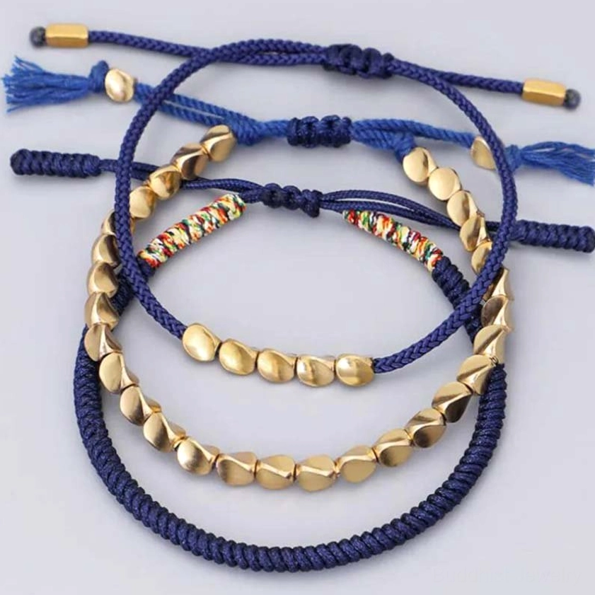 Buddhist copper bracelet set with mixed metal beads and tassel ends on light wooden background
