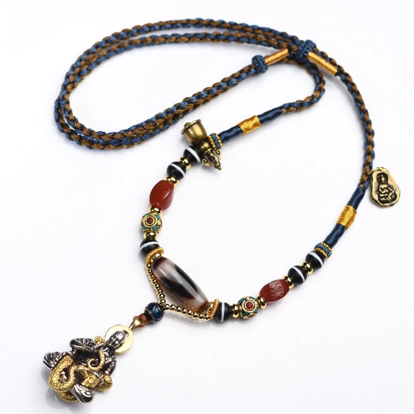 Flat-lay handmade dzi bead necklace with snake Buddha pendant on brown background