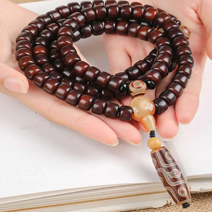 Handmade Buddhist dzi mala bracelet held in hands showing complete 108-bead assembly with jade spacers and spiritual protection pendant