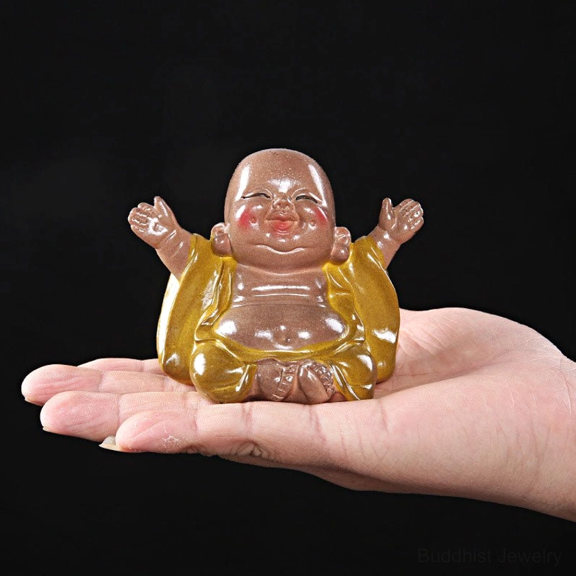 Hand-held laughing Buddha resin figurine display showing glossy yellow robe, cross-legged meditation pose, and smiling face