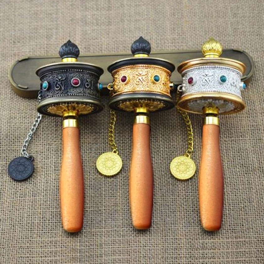Collection of three handcrafted Buddhist prayer wheels with unified wooden handles and mixed metal bodies featuring gemstone inlays and ornamental pendants