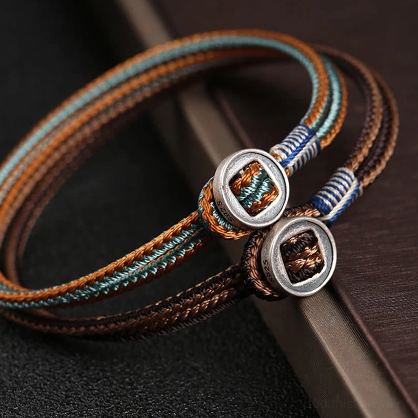 Artistic side angle of handcrafted woven silver string bracelet with brown blue cord design and metal decorative buckles