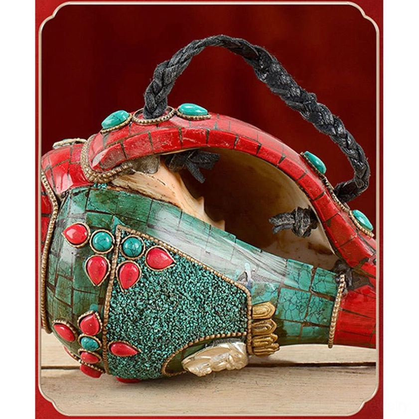 Hanging Buddhist conch shell decoration with braided black strap and exposed interior showing turquoise-red gemstone inlays
