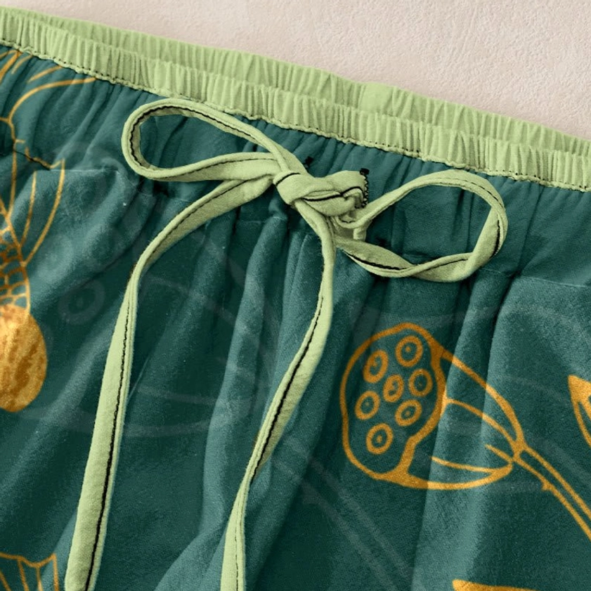 Close-up overhead view of light green elastic waistband with drawstring detail and topstitching on lotus print harem pants
