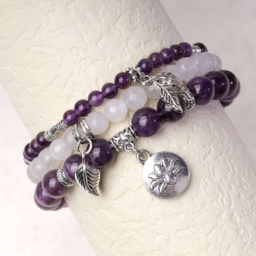 Healing crystal bracelet worn on wrist showing natural purple and white quartz beads with silver lotus charm and leaf pendant