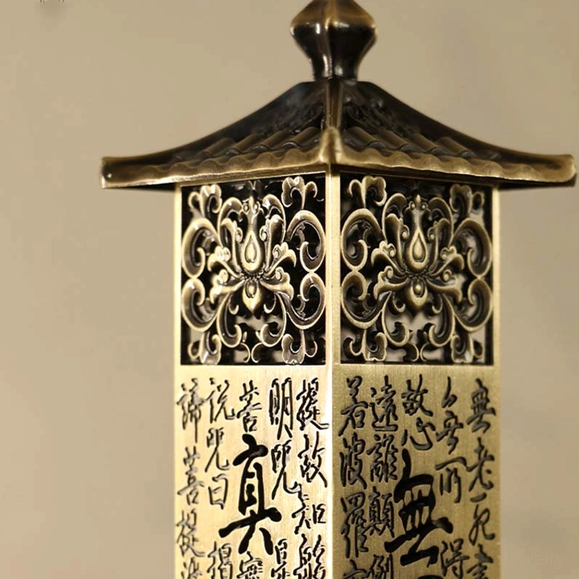 Incense burner detail showing hollowed floral carvings, handwritten sutra texts, and pagoda roof design