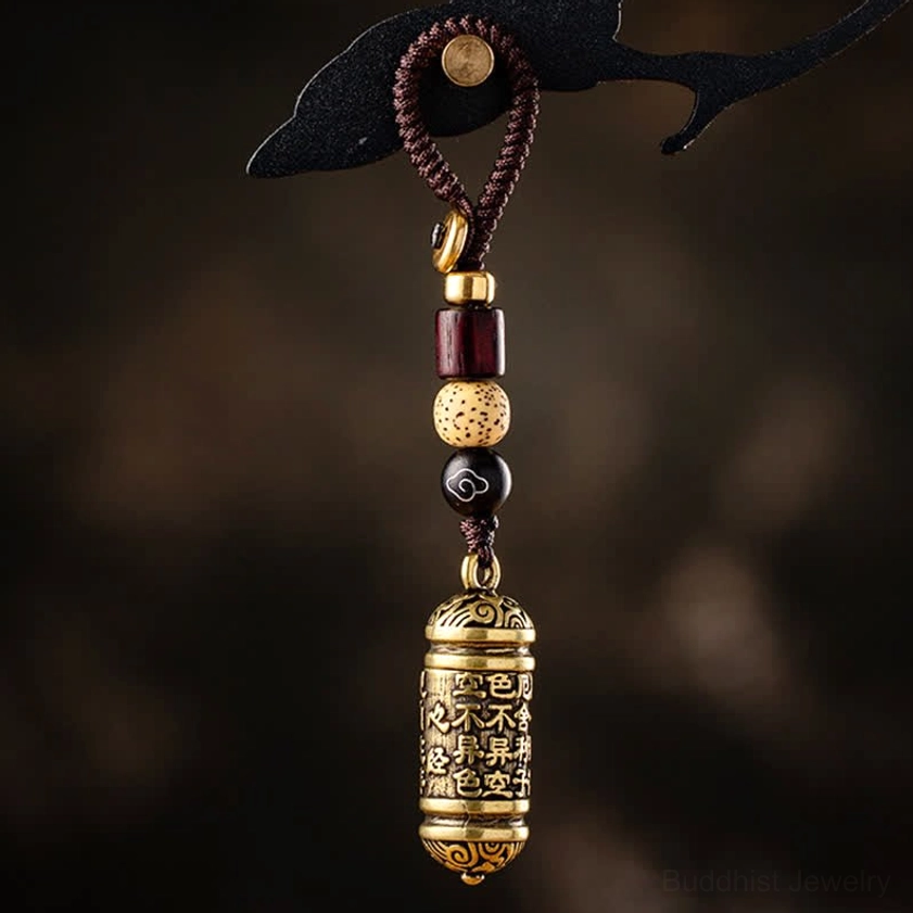 Heart Sutra copper keychain with engraved Buddhist sutra barrel pendant and braided beaded cord, overhead view