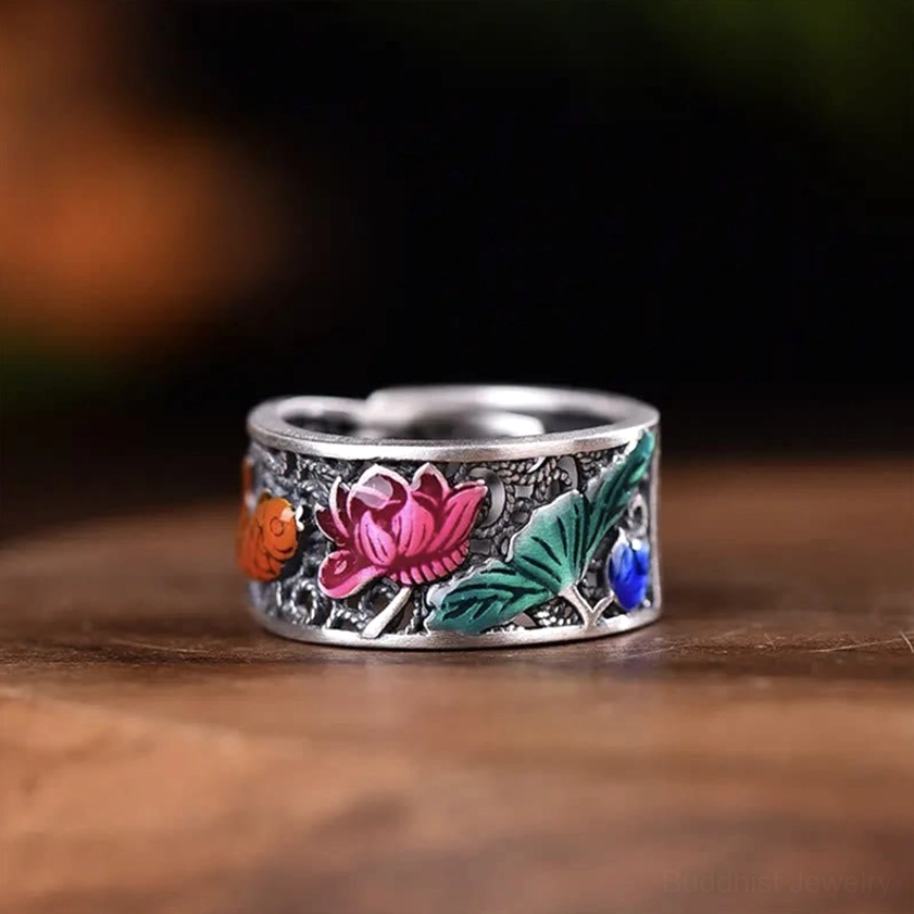 Front flat view of Heart Sutra lotus koi fish Buddhist ring featuring silver-toned copper base with pink lotus and orange koi decorations on dark wooden surface