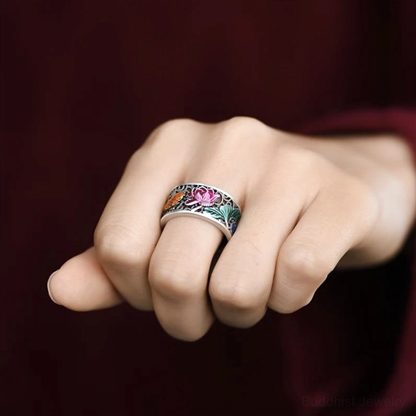 Close-up hand view of worn blue enamel lotus koi fish Heart Sutra ring on index finger showing vintage silver finish and colorful floral-fish motifs