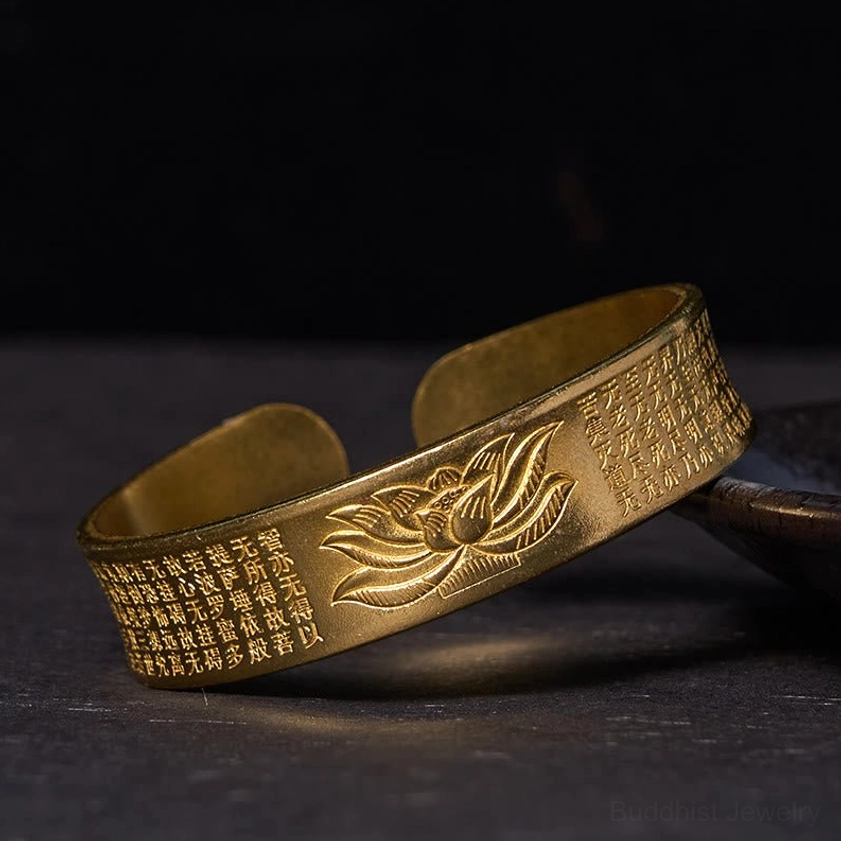 Heart Sutra lotus open cuff bracelet high angle view in retro brass finish with detailed engraved lotus and sutra on dark background