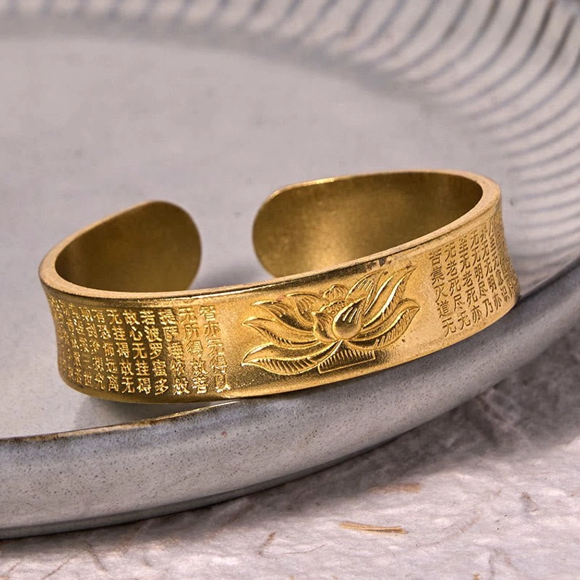 Buddhist lotus cuff bracelet side angle in retro brass displaying engraved lotus flower and Heart Sutra text open design