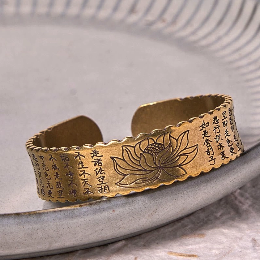Oblique top-down view of Heart Sutra lotus Buddhist cuff bracelet with scalloped rim and detailed lotus flower engraving in antiqued bronze