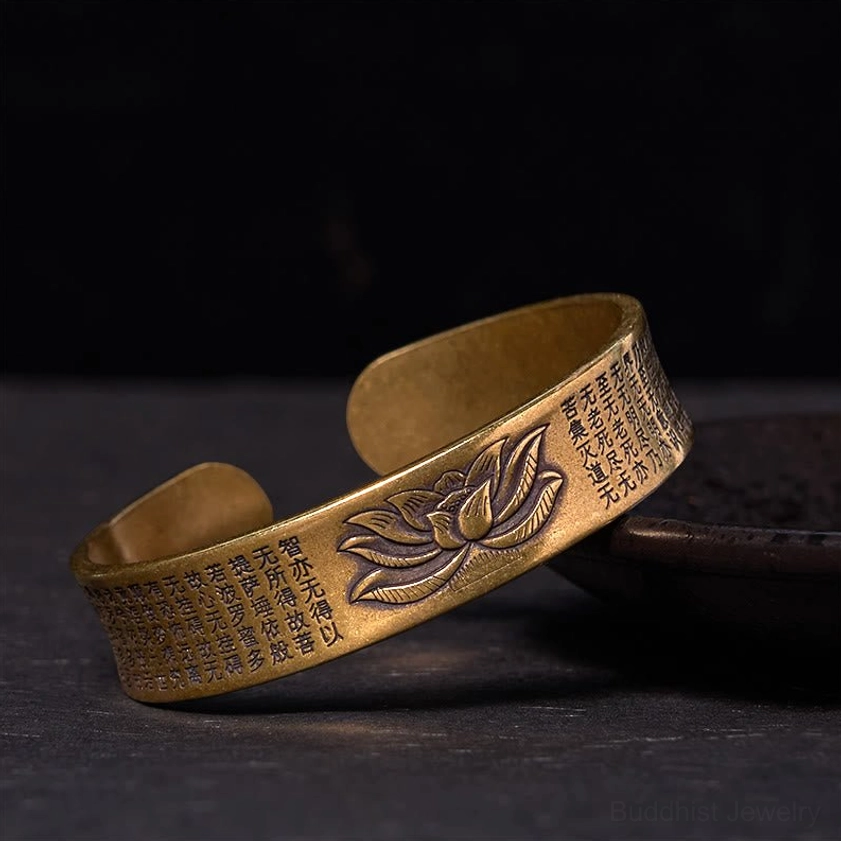 Heart Sutra lotus open cuff bracelet in polished brass, showing detailed lotus flower engraving and sutra inscriptions on dark surface