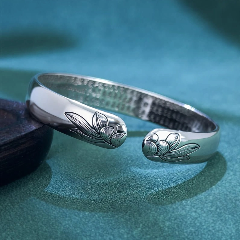 Open lotus cuff Buddhist bracelet left side oblique view showing lotus bud engravings on both ends with inner Buddhist scripture text