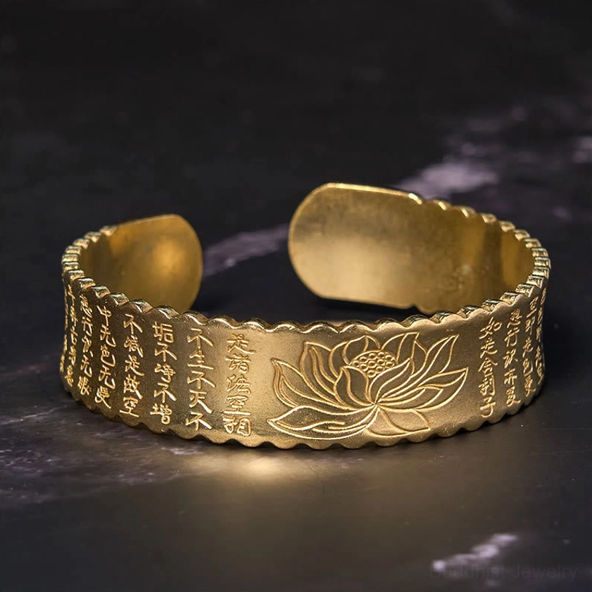 Close-up detail of Heart Sutra engraved text and lotus flower carving on open cuff bracelet brass bangle