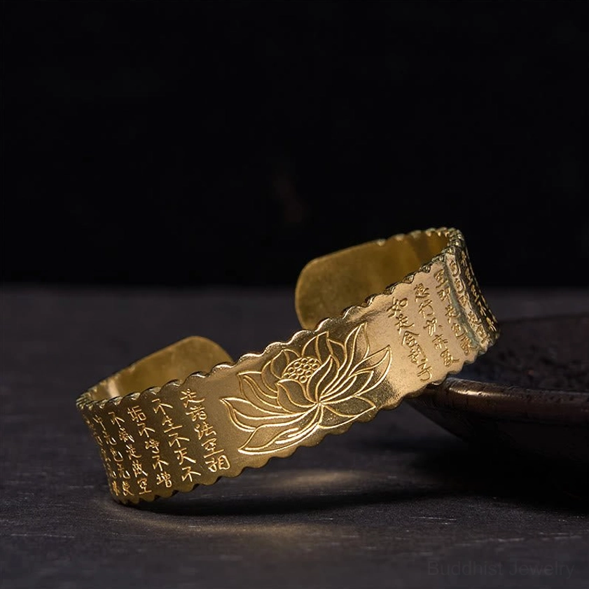Heart Sutra lotus Buddhist cuff bracelet with antiqued bronze finish and scalloped edge on small tray, showing sutra and lotus engravings