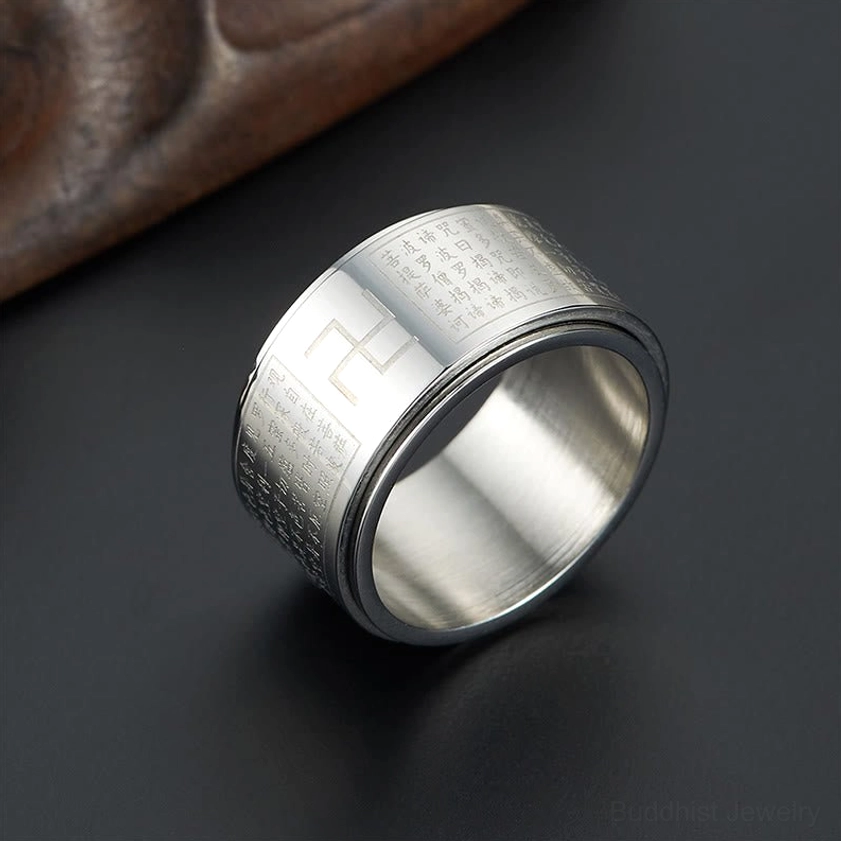 Silver Heart Sutra rotatable ring displayed on dark studio background showing engraved mantra and swastika design